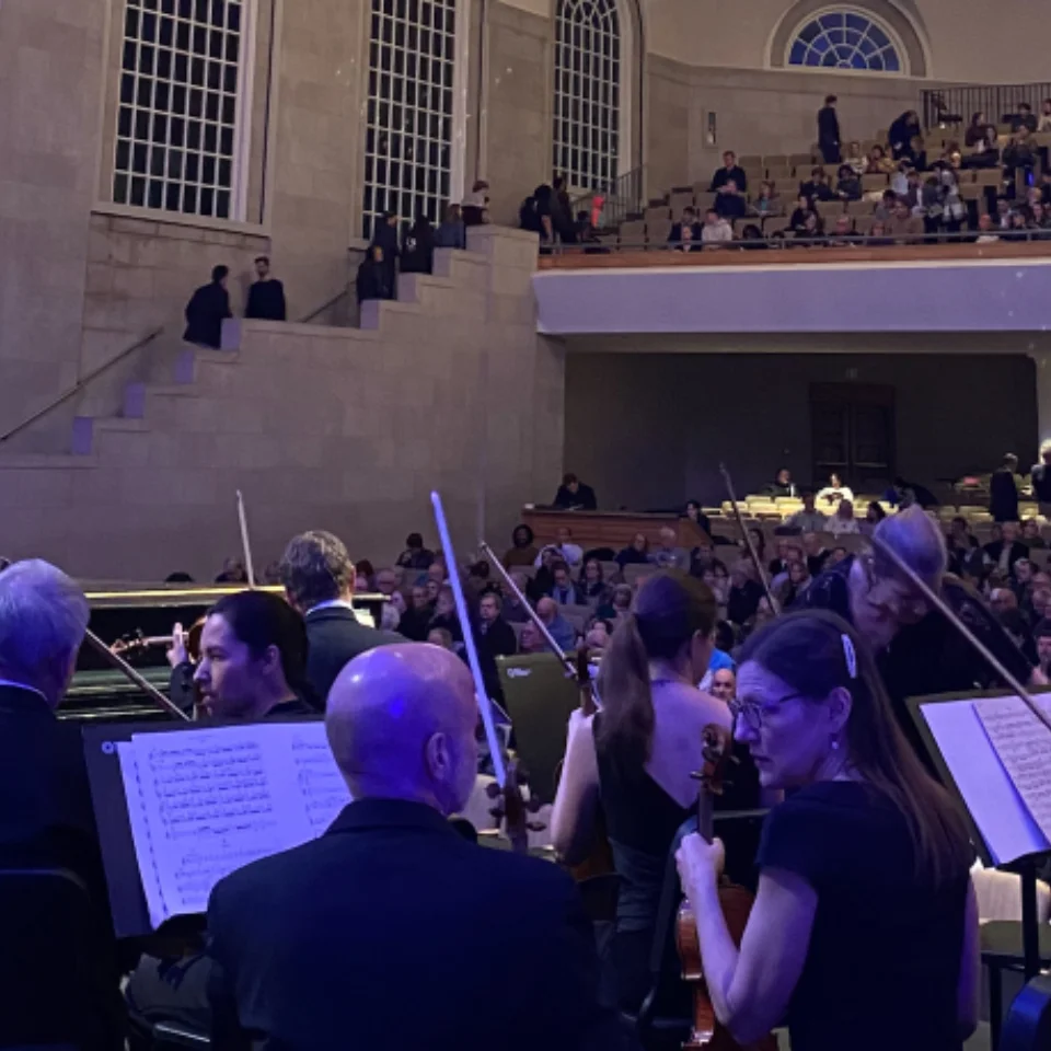 An Orchestra playing in front of an audience in a large concert hall