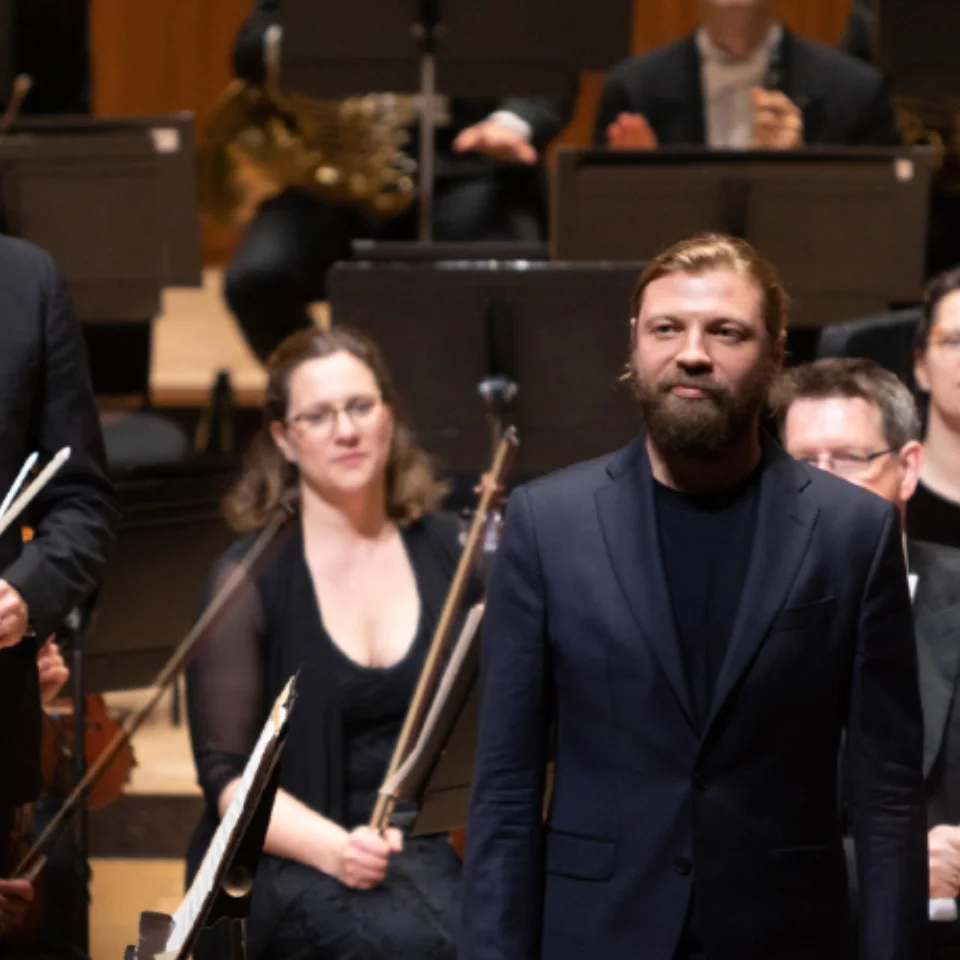 Vasily Petrenko and Denis Kozhukhin standing on stage to receive applause with the Orchestra behind them.