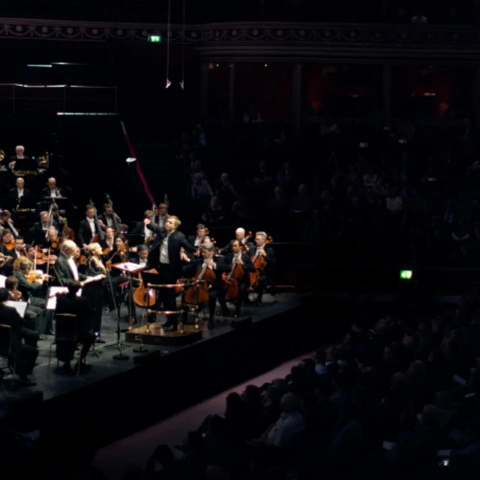 Vasily Petrenko conducting the Royal Philharmonic Orchestra in concert at the Royal Albert Hall, with the audience in darkness to their right