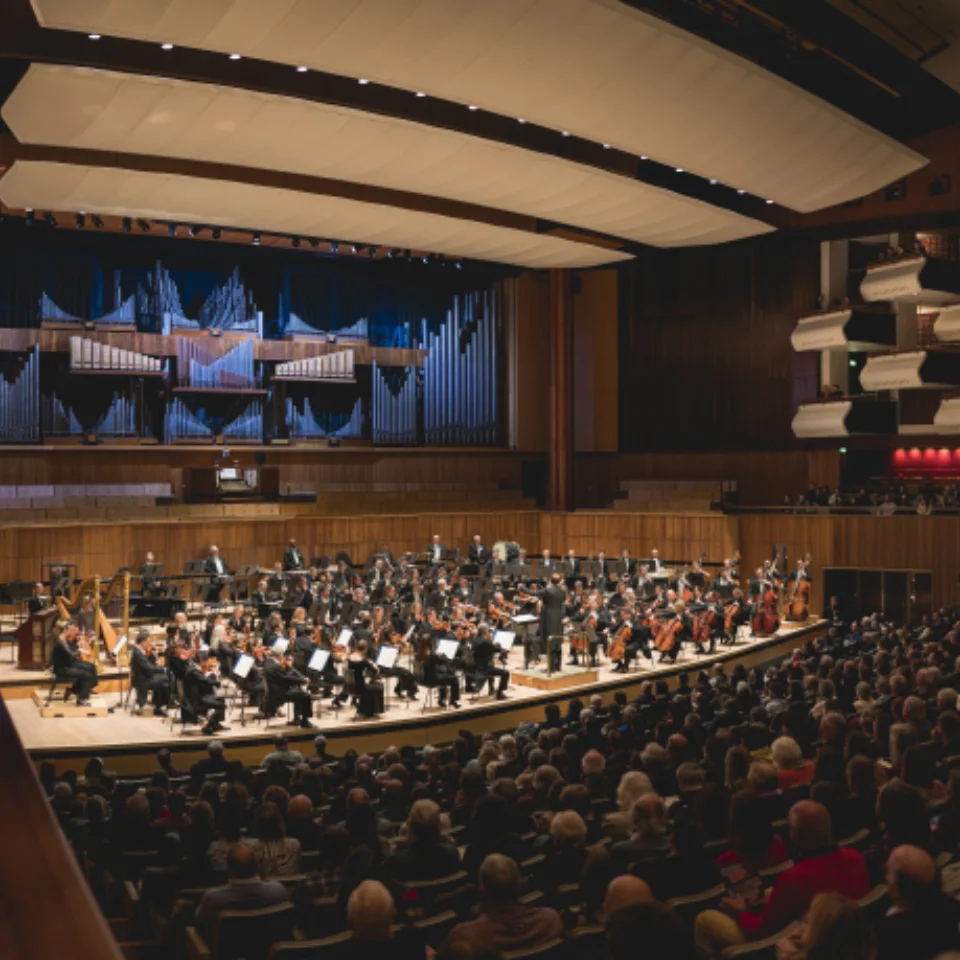 Orchestra playing to an audience in a large concert hall