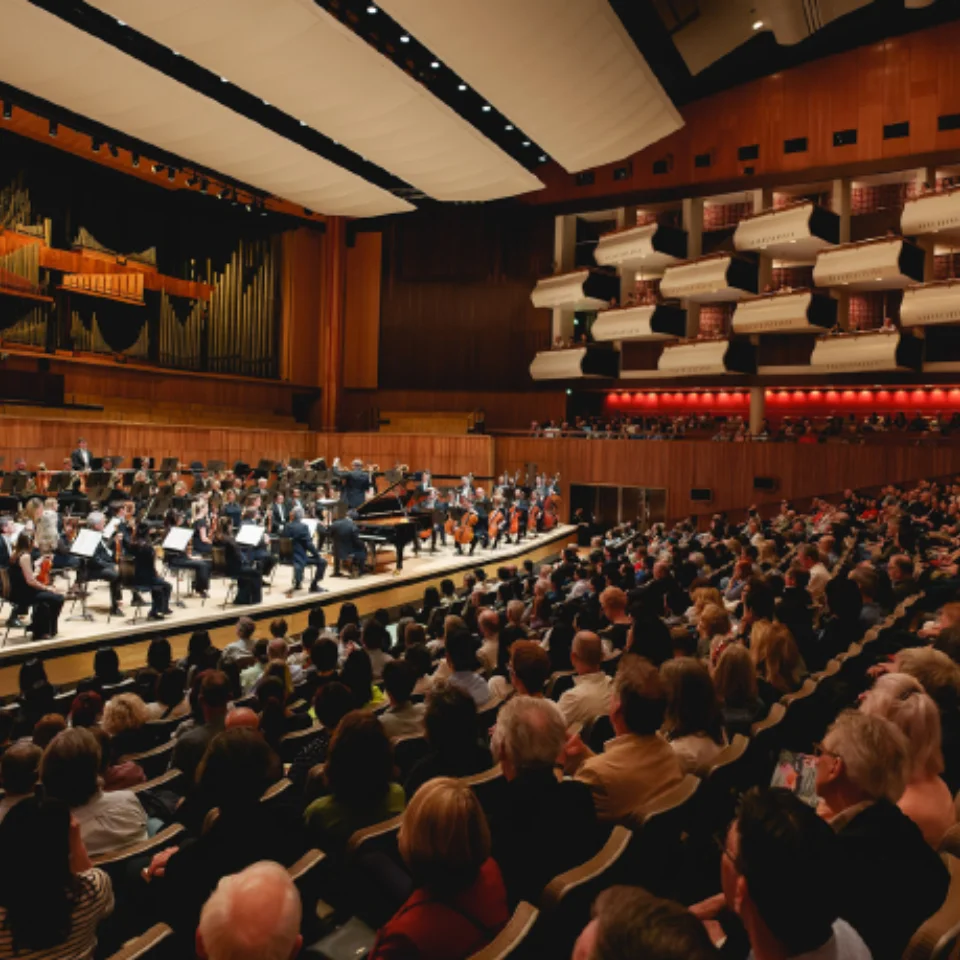Orchestra playing in a large concert hall in front of an audience