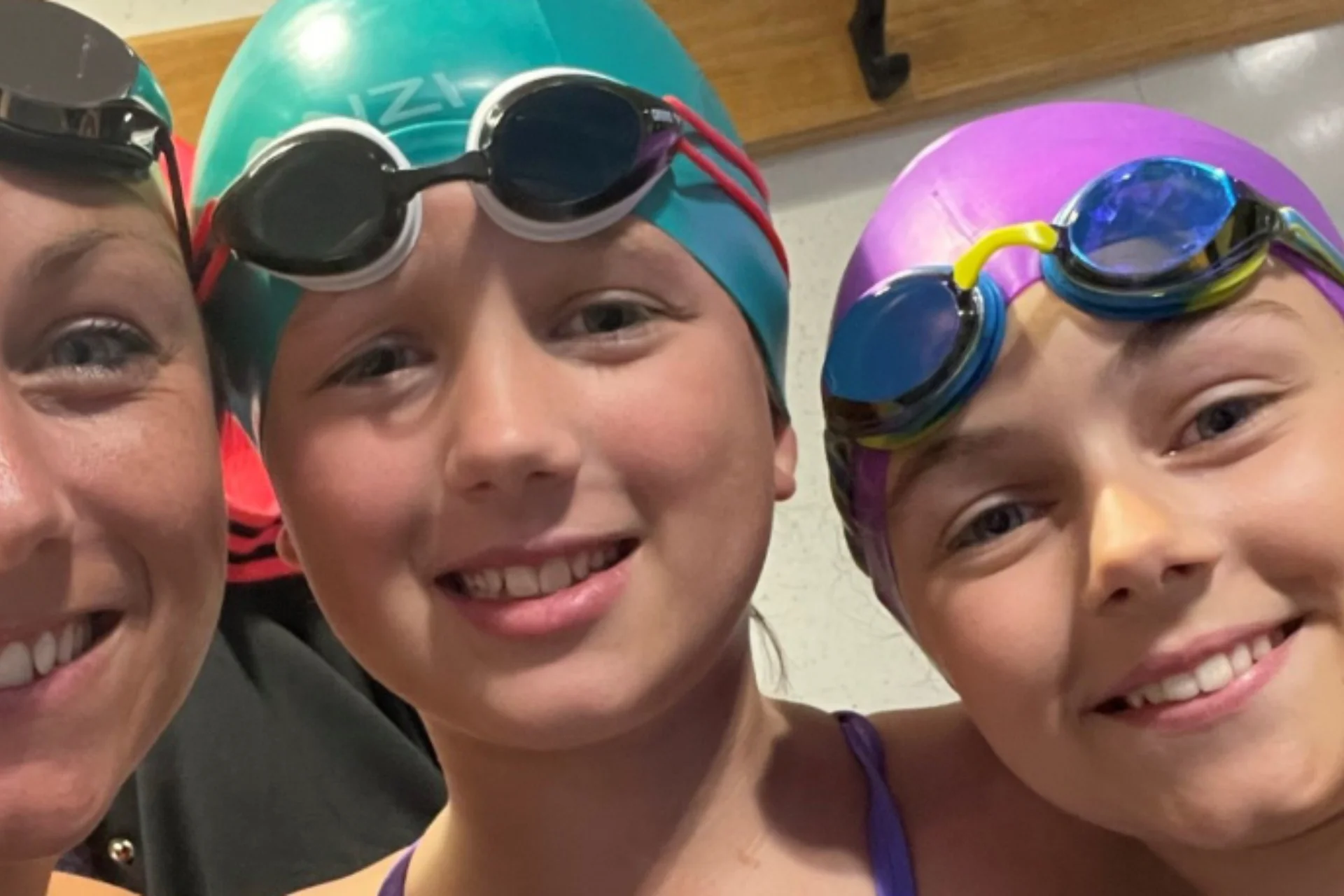 2 girls and a woman in swimming caps and swim goggles