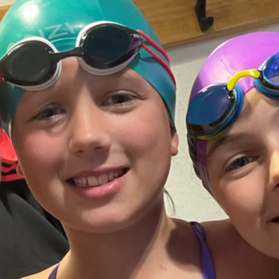 2 girls and a woman in swimming caps and swim goggles