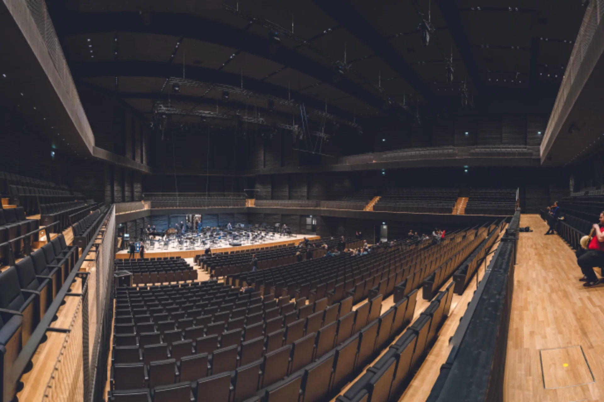 Orchestra playing in a large concert hall with 1 person in the audience