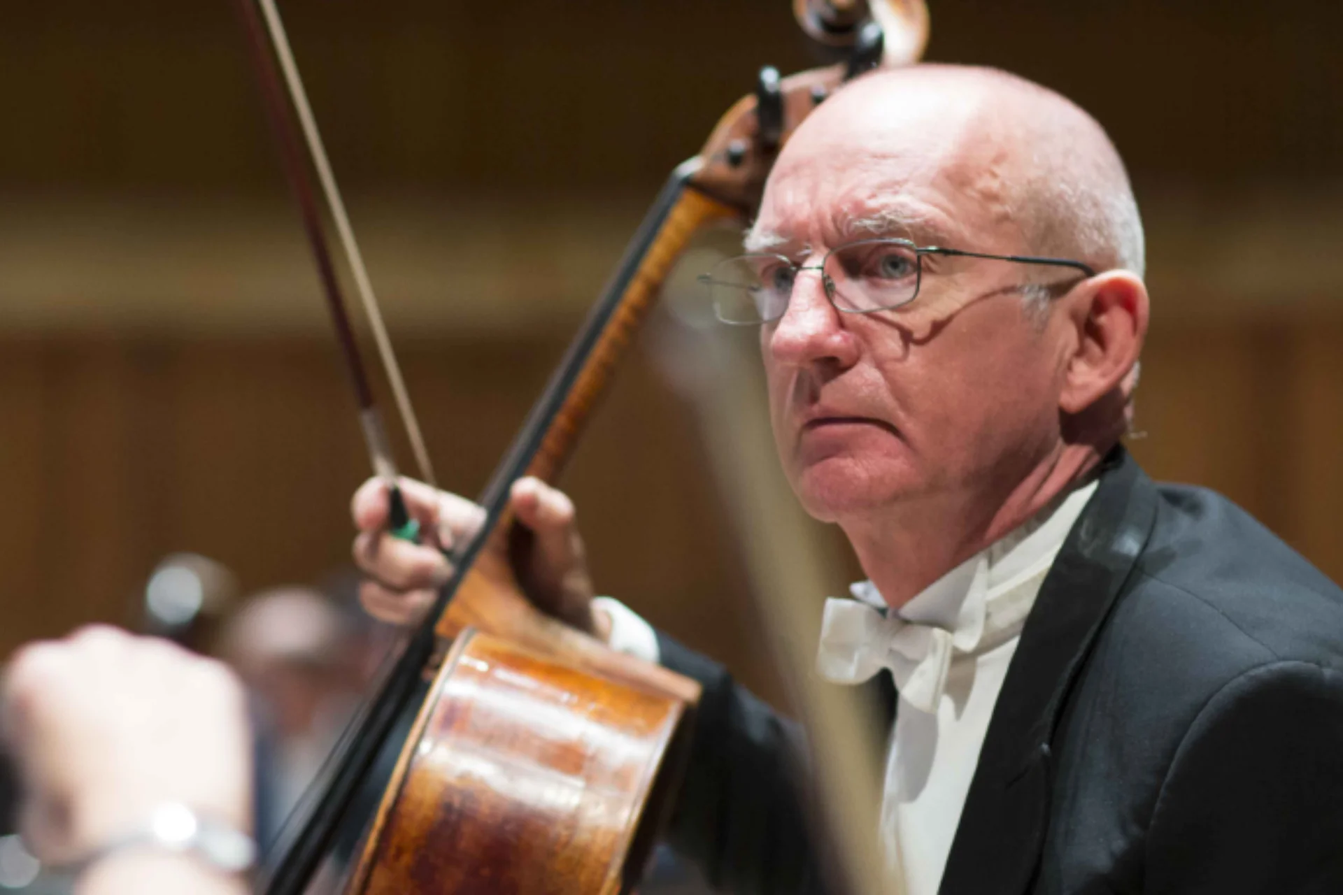 RPO Player William Heggart holding his cello in concert attire.